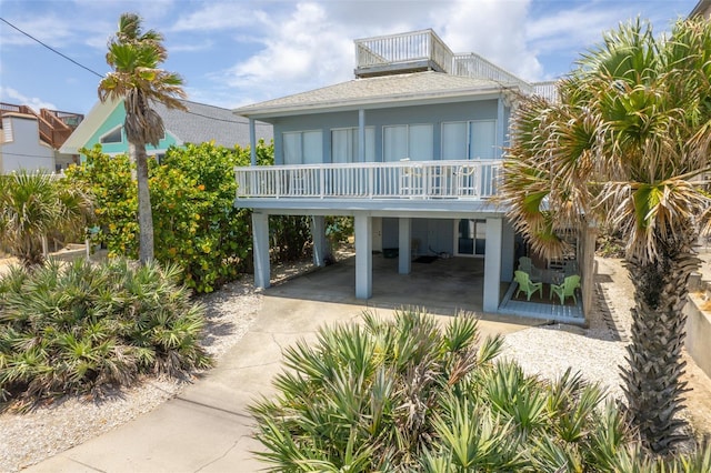 rear view of property featuring a balcony and a carport