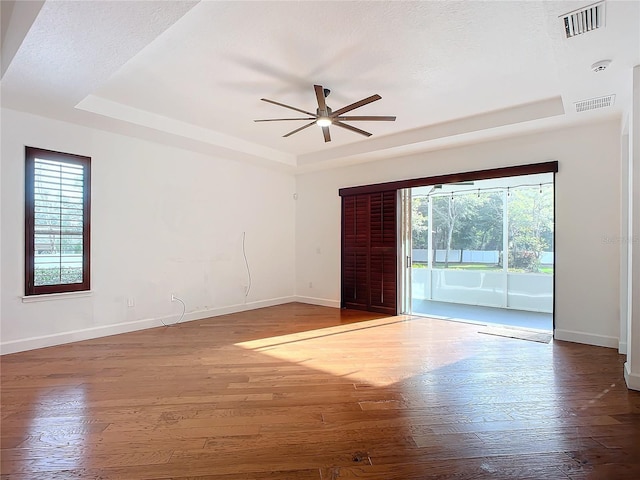 spare room with hardwood / wood-style floors, ceiling fan, and a raised ceiling