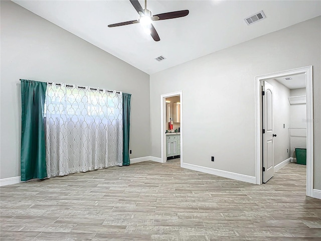 unfurnished bedroom with ensuite bathroom, high vaulted ceiling, ceiling fan, and light hardwood / wood-style flooring