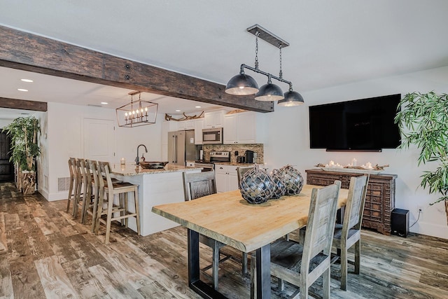 dining area with light wood-type flooring, beamed ceiling, and sink