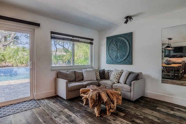 living room with dark wood-type flooring, a textured ceiling, and a healthy amount of sunlight