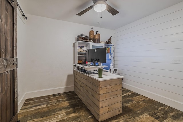 office space featuring ceiling fan, dark hardwood / wood-style floors, wood walls, and a barn door