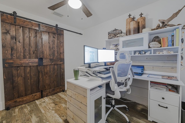 office area with ceiling fan, dark hardwood / wood-style floors, and a barn door