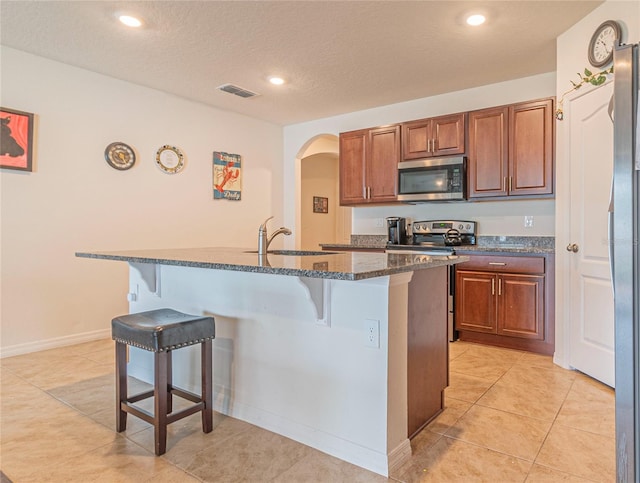 kitchen featuring a kitchen bar, a kitchen island with sink, sink, and appliances with stainless steel finishes