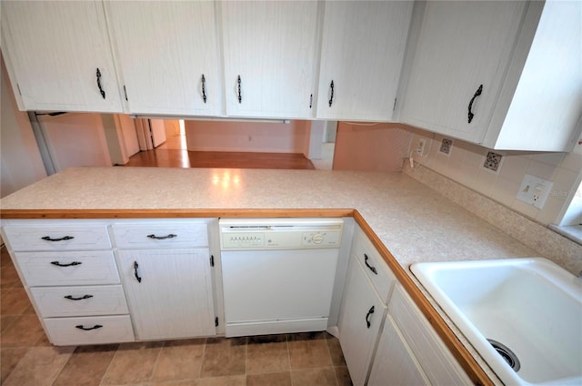 kitchen with kitchen peninsula, backsplash, white cabinets, sink, and dishwasher