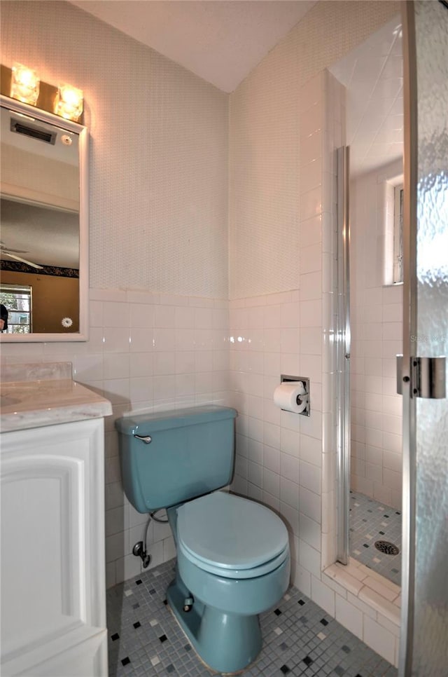 bathroom featuring tile patterned flooring, vanity, toilet, and tile walls