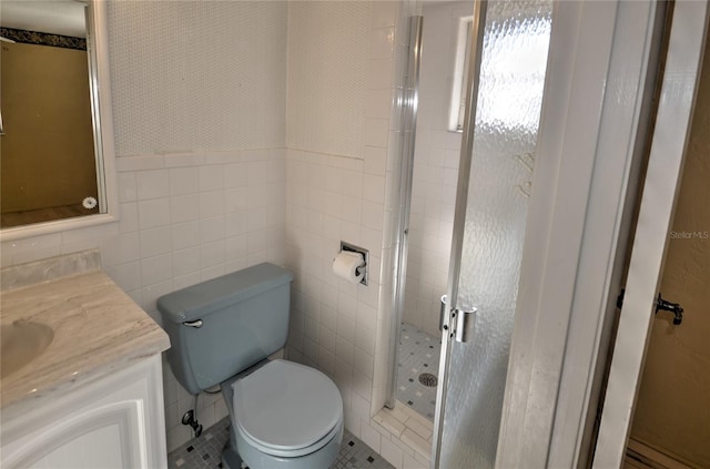 bathroom featuring vanity, a shower with door, toilet, and tile walls