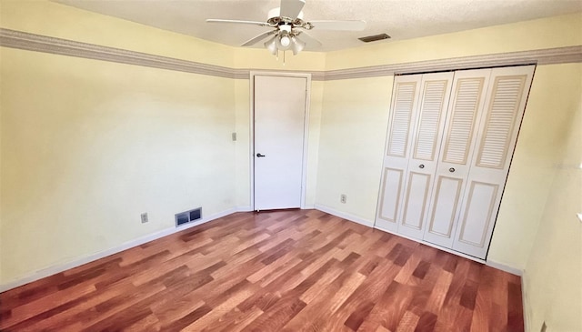 unfurnished bedroom featuring a closet, ceiling fan, hardwood / wood-style floors, and a textured ceiling