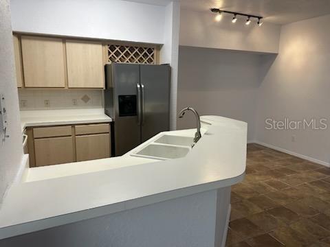 kitchen with stainless steel fridge with ice dispenser, tasteful backsplash, light brown cabinetry, and sink