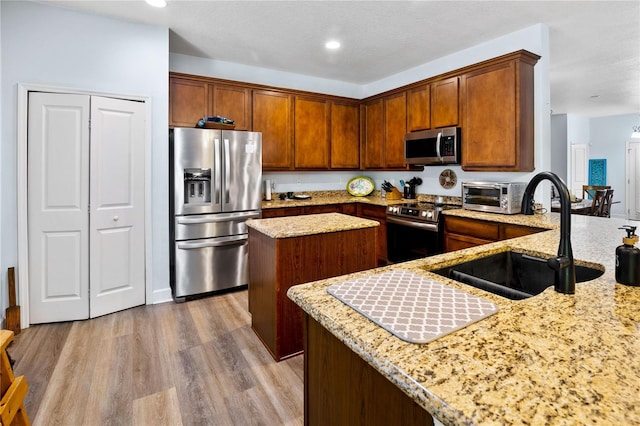 kitchen featuring light hardwood / wood-style floors, sink, light stone countertops, and stainless steel appliances