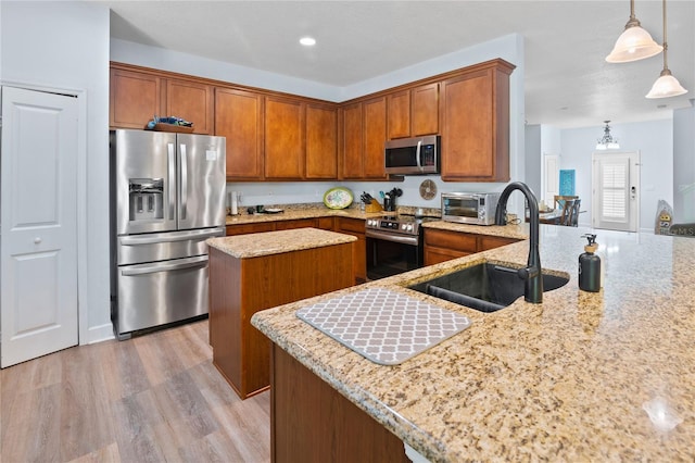 kitchen featuring light stone countertops, appliances with stainless steel finishes, decorative light fixtures, and sink