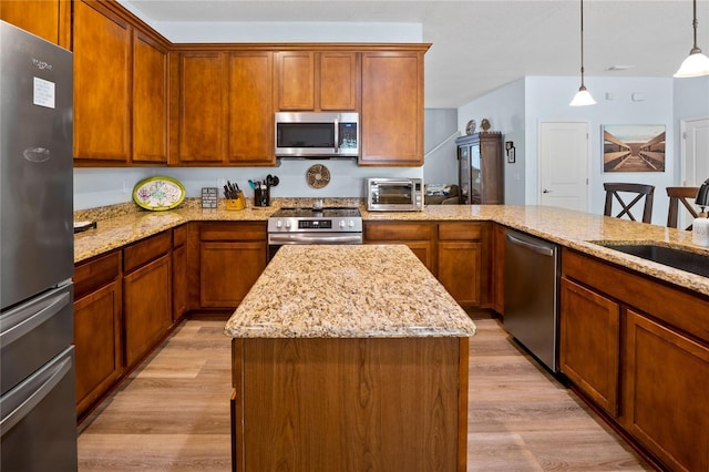 kitchen featuring a center island, sink, light hardwood / wood-style flooring, appliances with stainless steel finishes, and decorative light fixtures