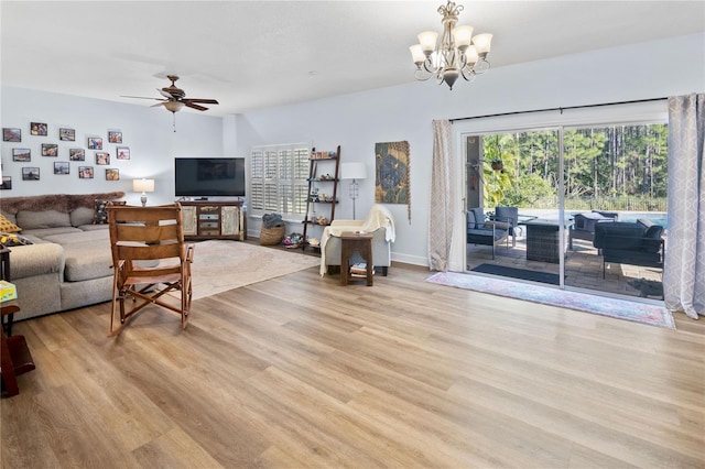 living room featuring ceiling fan with notable chandelier and light wood-type flooring