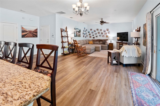 dining area featuring wood-type flooring and ceiling fan with notable chandelier