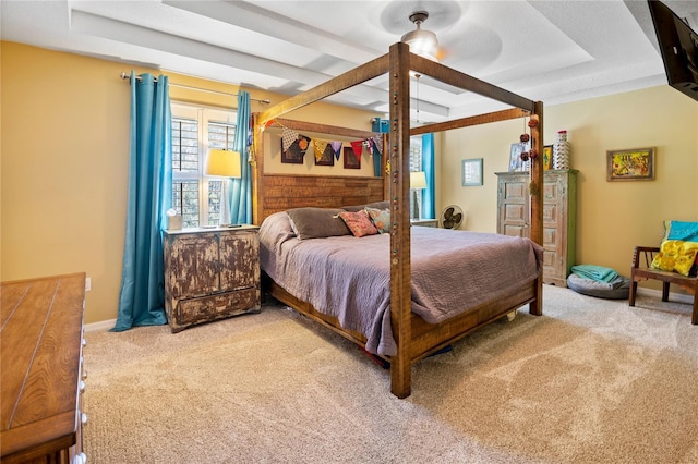 bedroom with ceiling fan, light colored carpet, and a tray ceiling