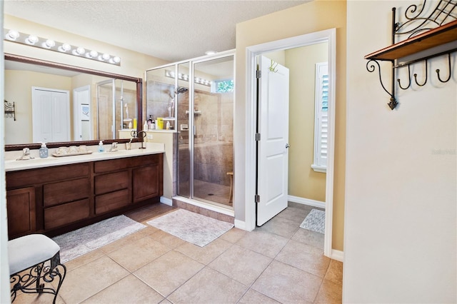 bathroom with tile patterned floors, vanity, walk in shower, and a textured ceiling