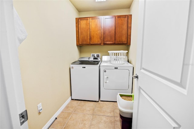 laundry area featuring washer and dryer, light tile patterned flooring, and cabinets