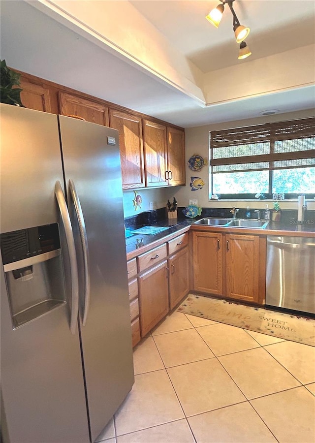 kitchen with sink, rail lighting, stainless steel appliances, a raised ceiling, and light tile patterned floors