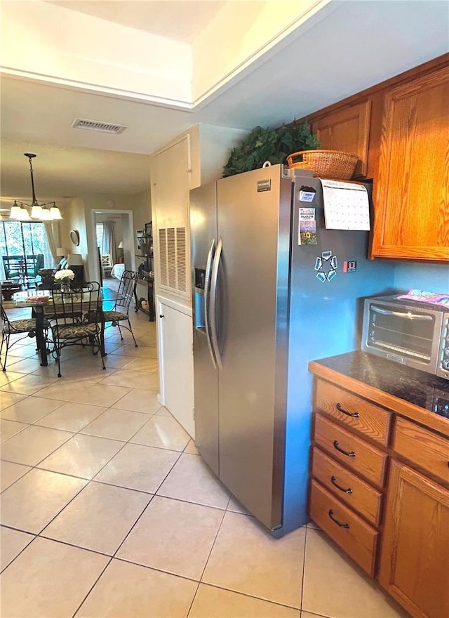 kitchen with stainless steel fridge, light tile patterned floors, and pendant lighting