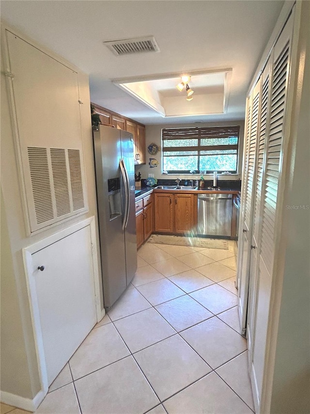 kitchen featuring light tile patterned floors, stainless steel appliances, a tray ceiling, and sink