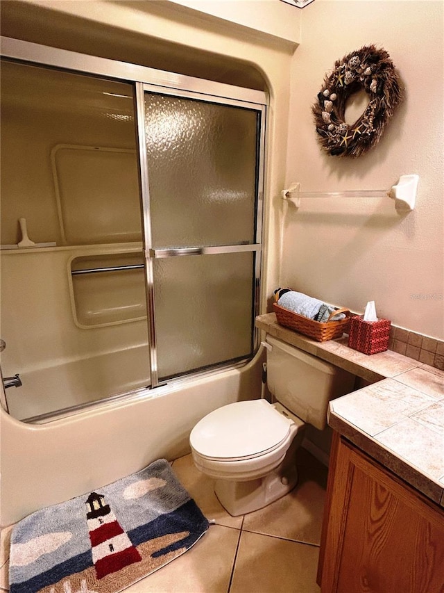 full bathroom featuring toilet, vanity, tile patterned floors, and bath / shower combo with glass door