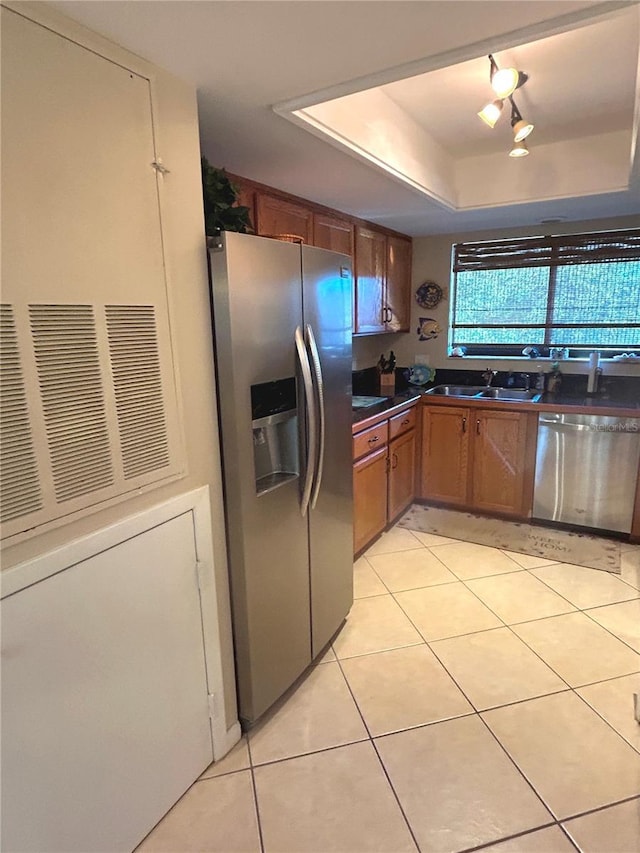 kitchen featuring light tile patterned floors, sink, appliances with stainless steel finishes, and a tray ceiling