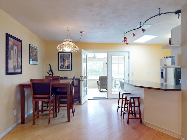 dining space featuring a skylight, french doors, light hardwood / wood-style floors, and track lighting