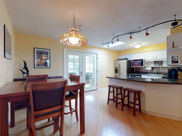 dining space with sink, french doors, and light hardwood / wood-style flooring