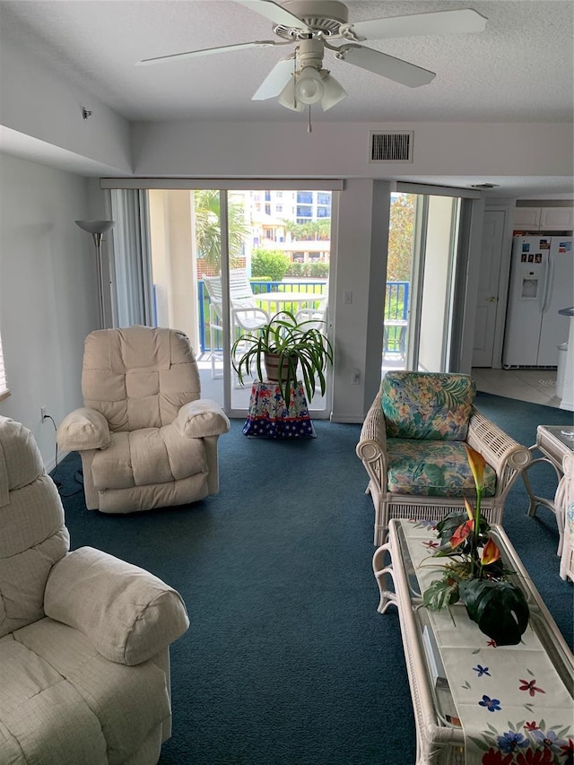 carpeted living room featuring a textured ceiling, ceiling fan, and a healthy amount of sunlight