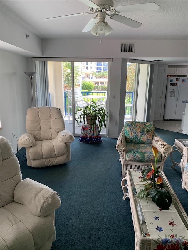 carpeted living room with ceiling fan and a textured ceiling