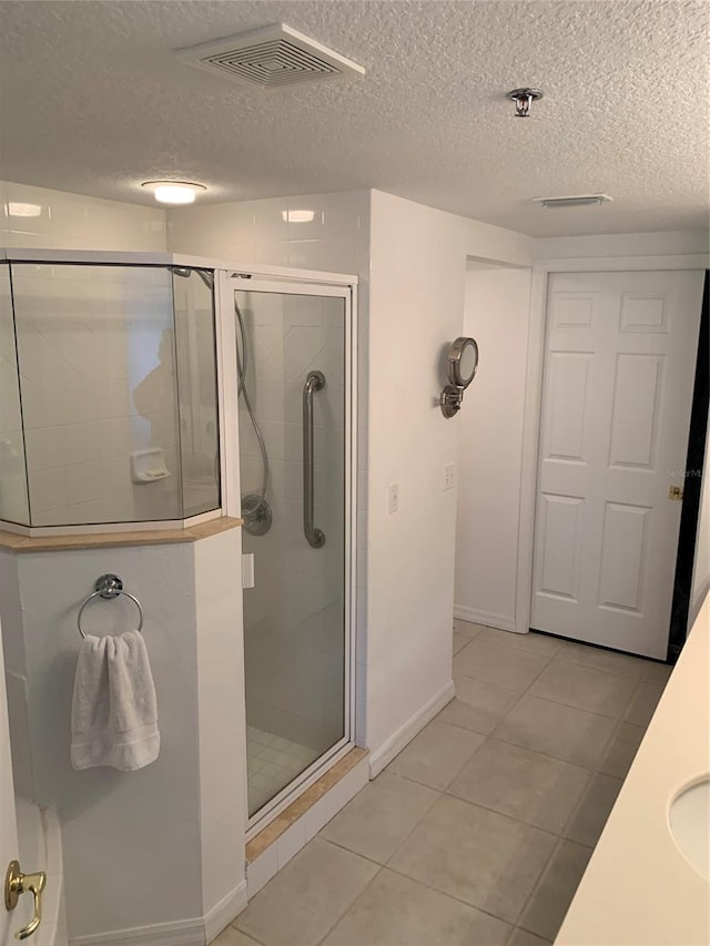 bathroom with an enclosed shower, tile patterned floors, and a textured ceiling