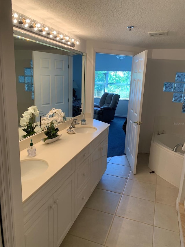 bathroom featuring a textured ceiling, a bathing tub, tile patterned flooring, and vanity