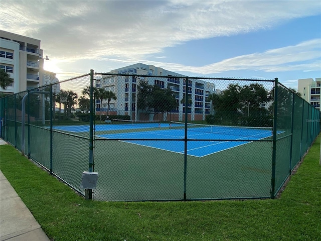 view of tennis court with a yard