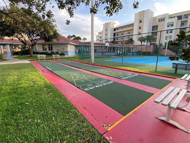 view of home's community featuring tennis court and a lawn