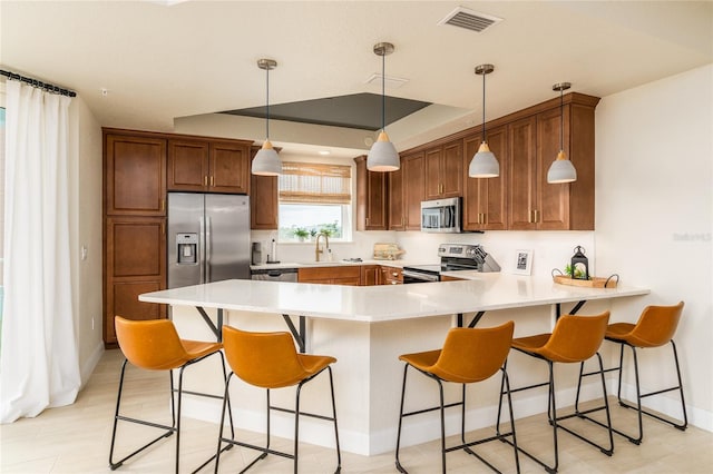 kitchen featuring sink, kitchen peninsula, decorative light fixtures, a breakfast bar, and appliances with stainless steel finishes