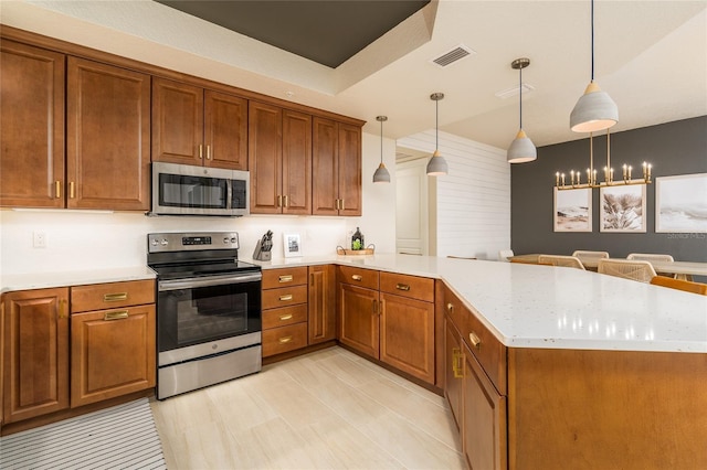 kitchen with kitchen peninsula, a notable chandelier, decorative light fixtures, and appliances with stainless steel finishes