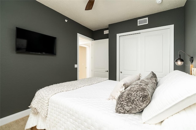 bedroom with carpet flooring, a textured ceiling, a closet, and ceiling fan