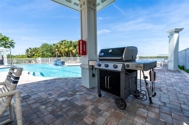 view of patio with area for grilling, pool water feature, and a community pool