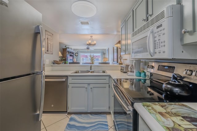 kitchen featuring gray cabinetry, ceiling fan with notable chandelier, sink, appliances with stainless steel finishes, and light tile patterned flooring