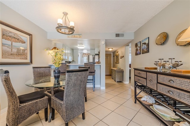 tiled dining room with a chandelier and a textured ceiling