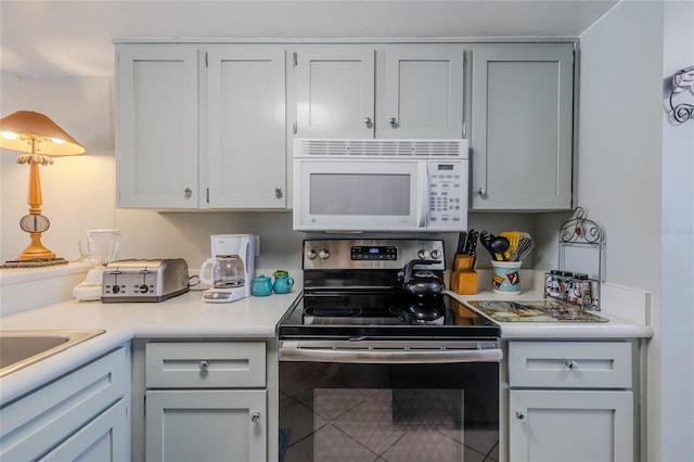 kitchen with stainless steel electric stove and tile patterned flooring