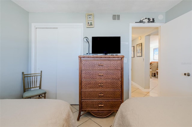 bedroom with light tile patterned floors, a textured ceiling, and a closet