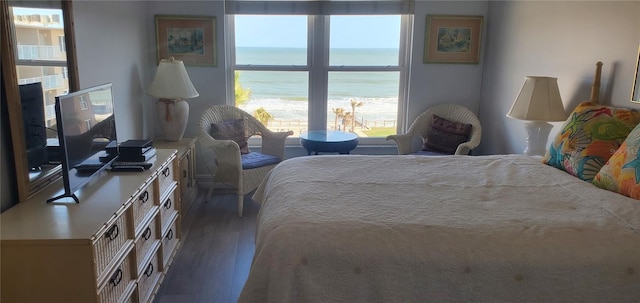 bedroom featuring dark hardwood / wood-style flooring, a water view, and multiple windows