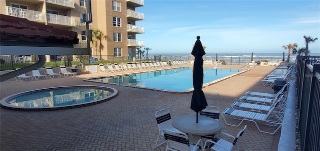 view of swimming pool with a patio, a water view, and a hot tub