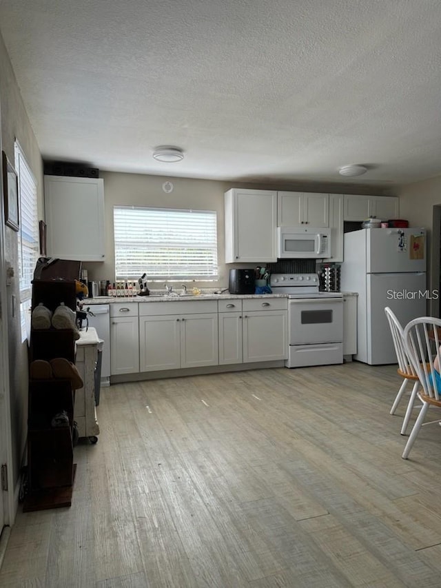 kitchen with white cabinetry, light hardwood / wood-style flooring, white appliances, and sink