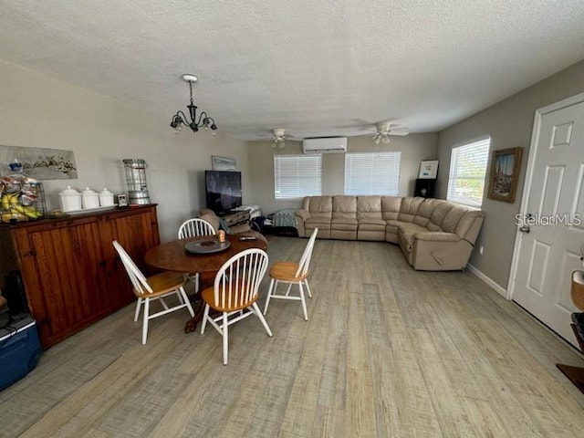 dining room with an AC wall unit, light hardwood / wood-style flooring, a textured ceiling, and ceiling fan with notable chandelier