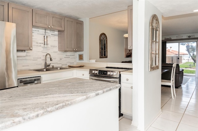 kitchen with backsplash, sink, light tile patterned floors, light brown cabinetry, and appliances with stainless steel finishes