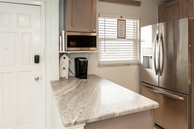 kitchen featuring light stone countertops, plenty of natural light, and appliances with stainless steel finishes