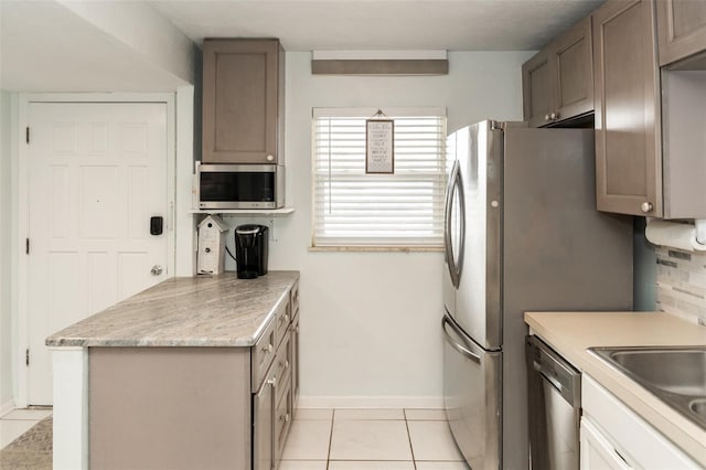 kitchen with light tile patterned floors, sink, appliances with stainless steel finishes, and tasteful backsplash