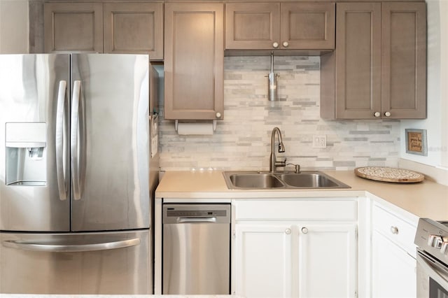 kitchen with stove, sink, stainless steel fridge with ice dispenser, tasteful backsplash, and white cabinetry